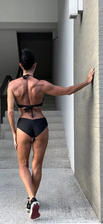Anna walking up a staircase, viewed from behind, with one hand against the wall.